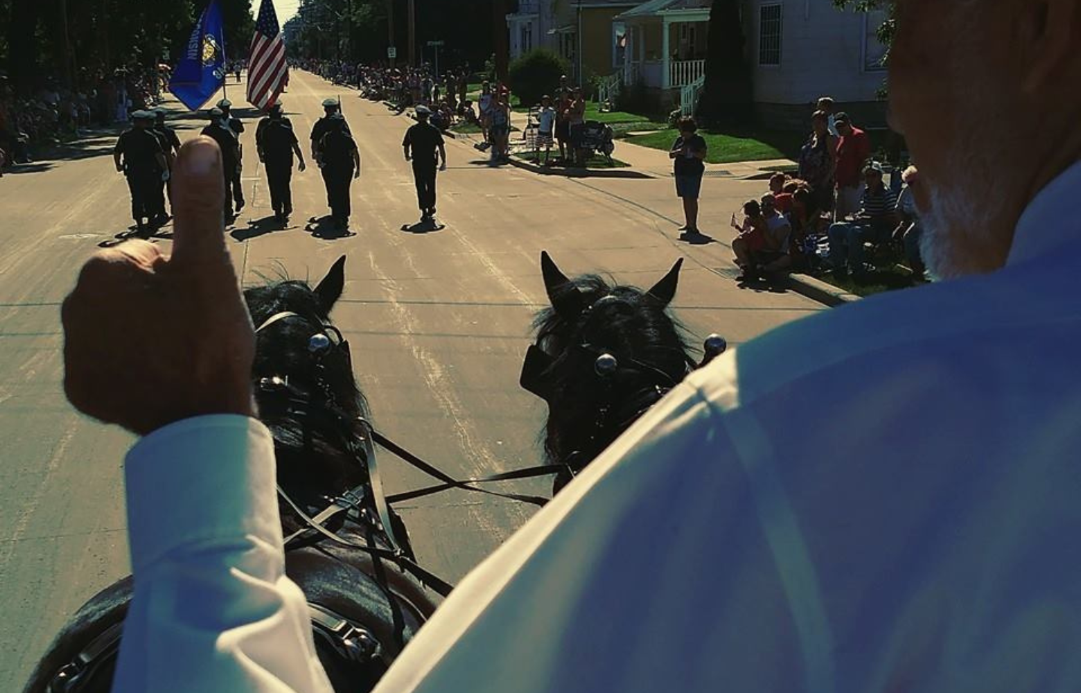 Rodger Cavanaugh leading a horse-drawn carriage ride during a vibrant community event, spreading joy and creating memorable experiences.