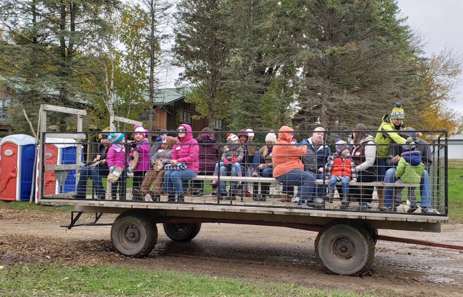 A group of people excitedly beginning their hay ride, organized by Cavanaugh Carriages, showcasing a fun and festive outdoor experience