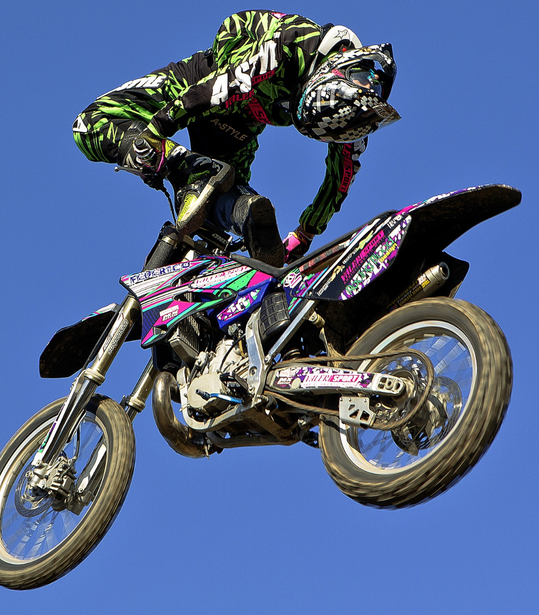 A skilled FMX rider executing an impressive aerial trick during a freestyle motocross performance, showcasing adrenaline and precision