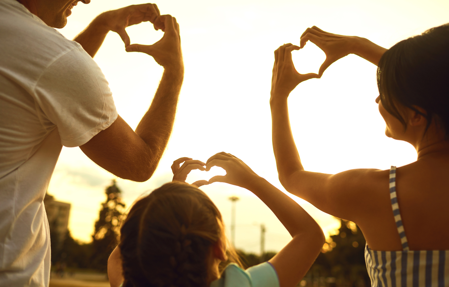 A family forming a heart shape with their hands, symbolizing the warmth, love, and togetherness of family reunions and special gatherings hosted by Cavanaugh Carriages.